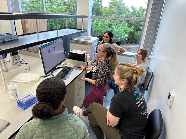 Hands-on lab with students gathered around a flow cytometer workstation